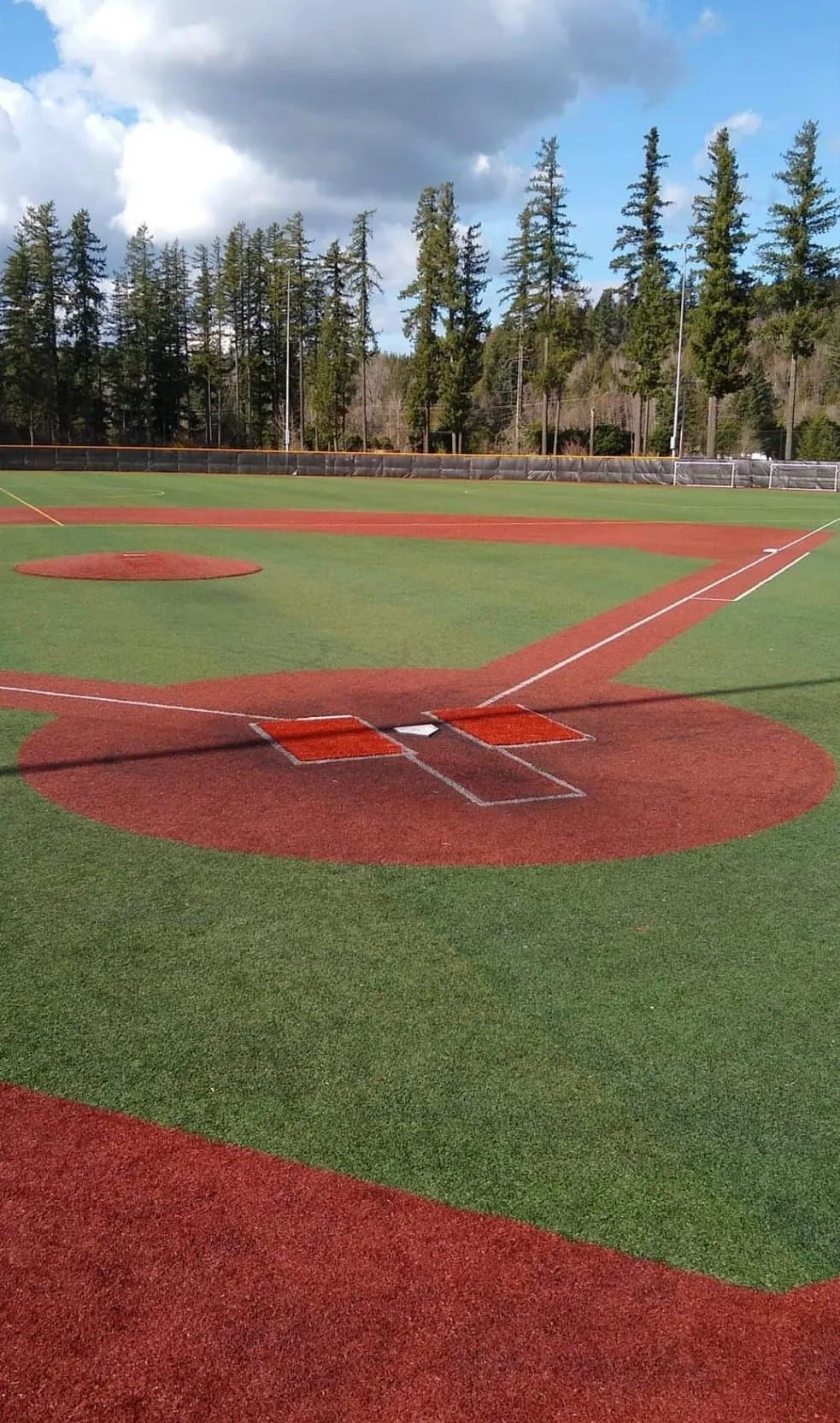 Baseball infield turf installation with red infield material and synthetic grass outfield