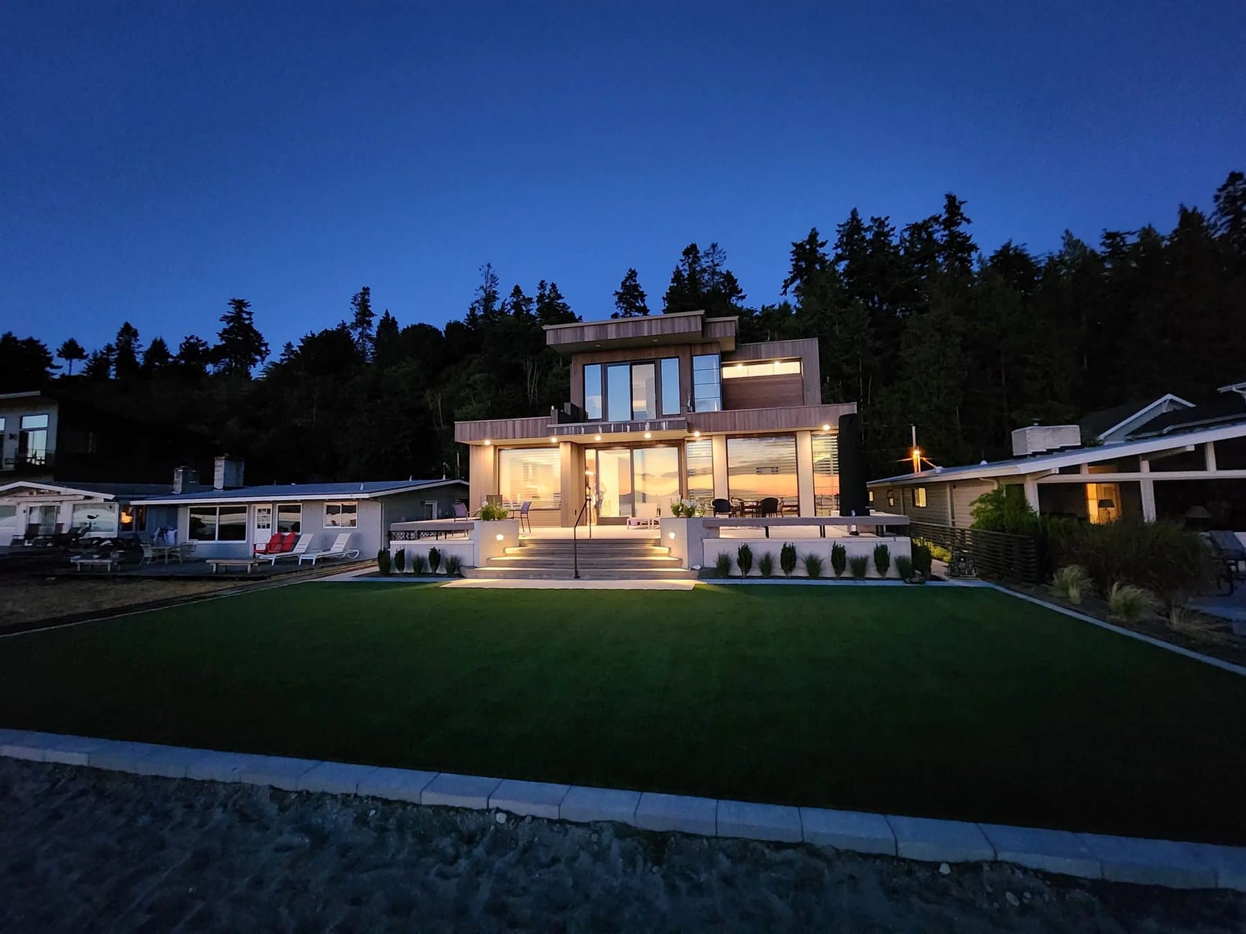 Modern backyard artificial turf lawn glowing at dusk beside an outdoor living space