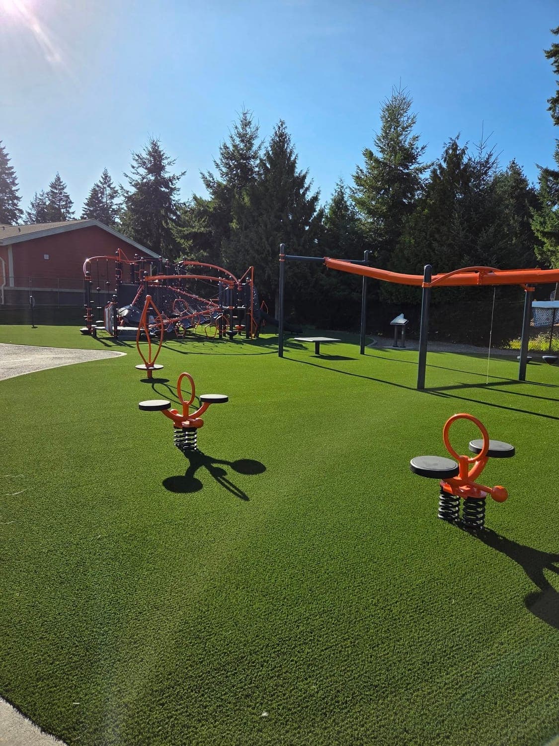 Backyard playground with spring riders and a play structure over cushioned artificial turf