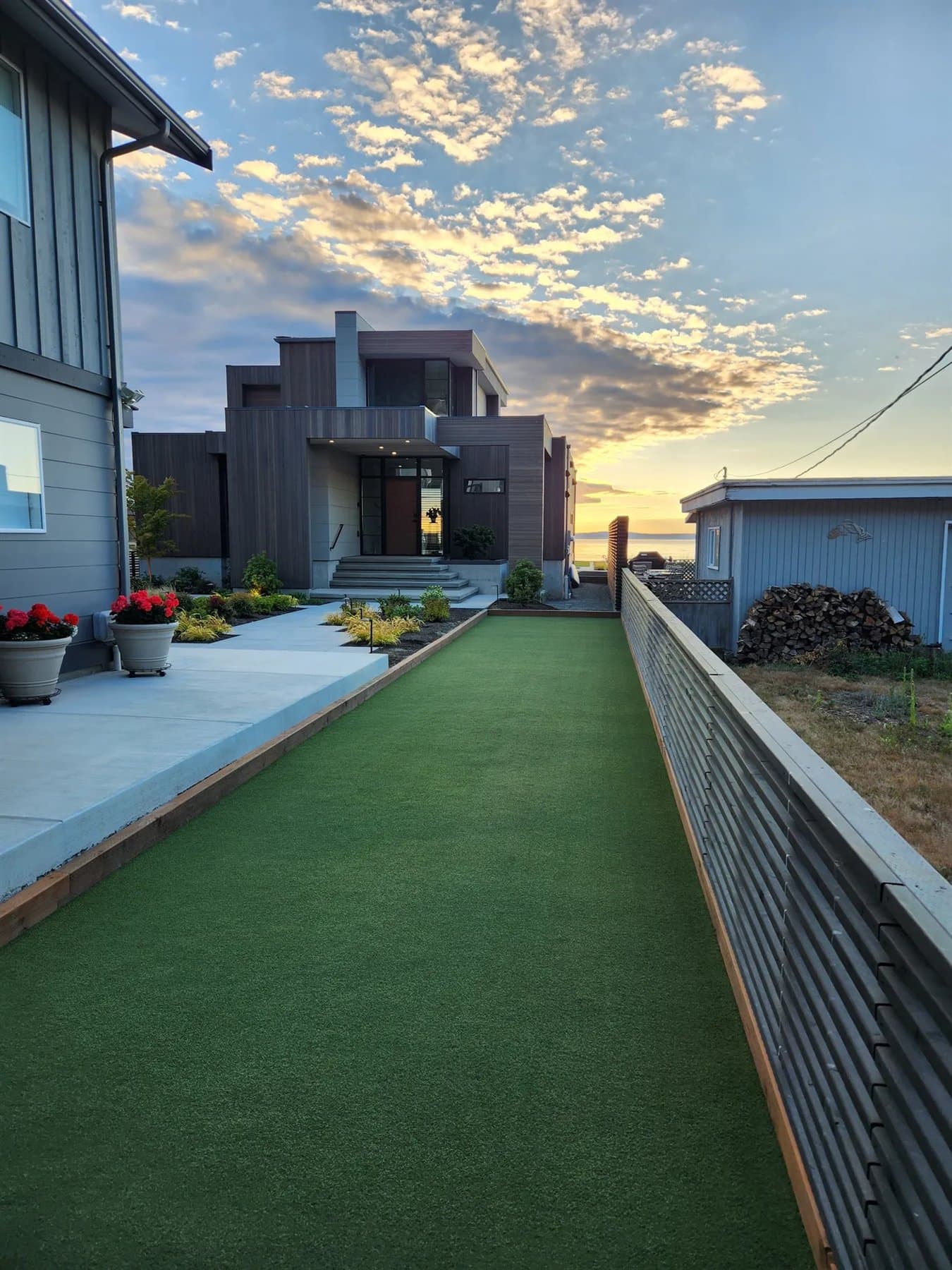 Narrow side-yard artificial turf run between a modern home and raised planters