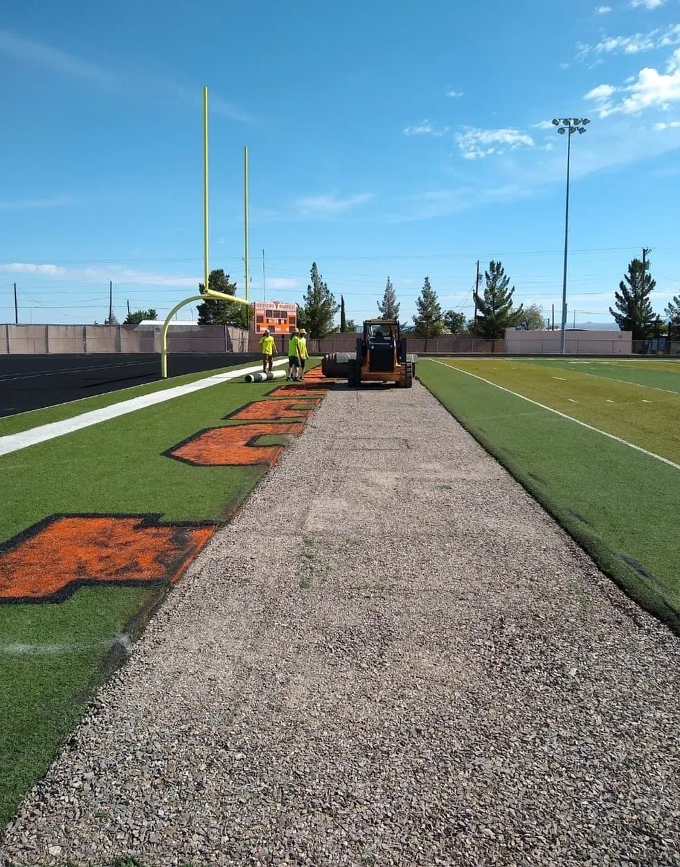 Sports field sideline with artificial turf installation and colorful inlay work