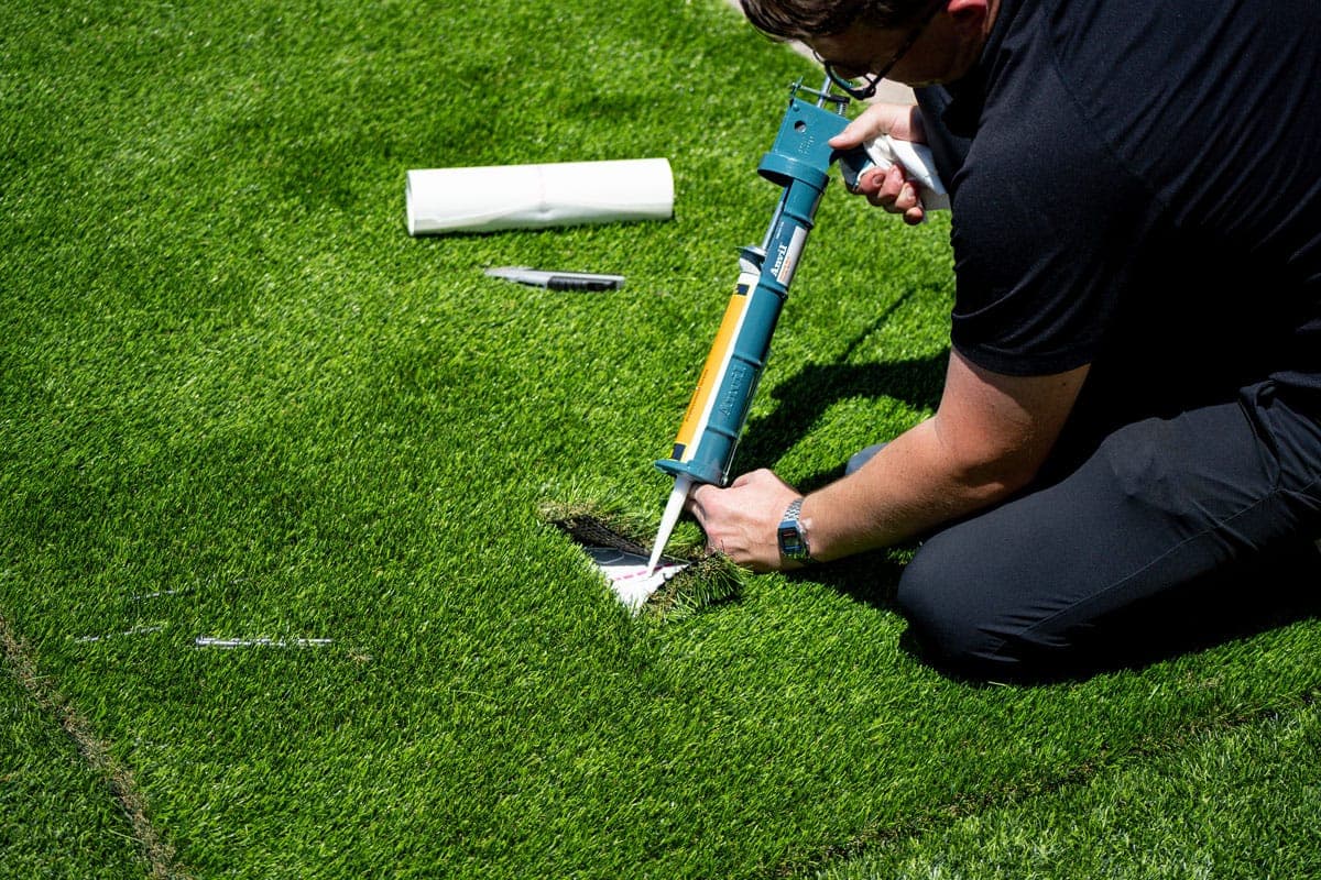 Synthetic Turf Solutions installer applying adhesive and seaming artificial turf